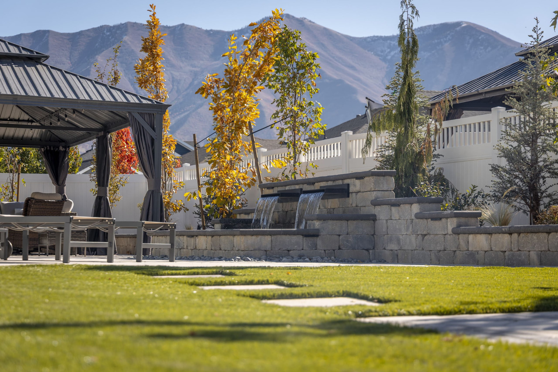 Stone water wall with scuppers and a gazebo, Wasatch mountains in fall color behind