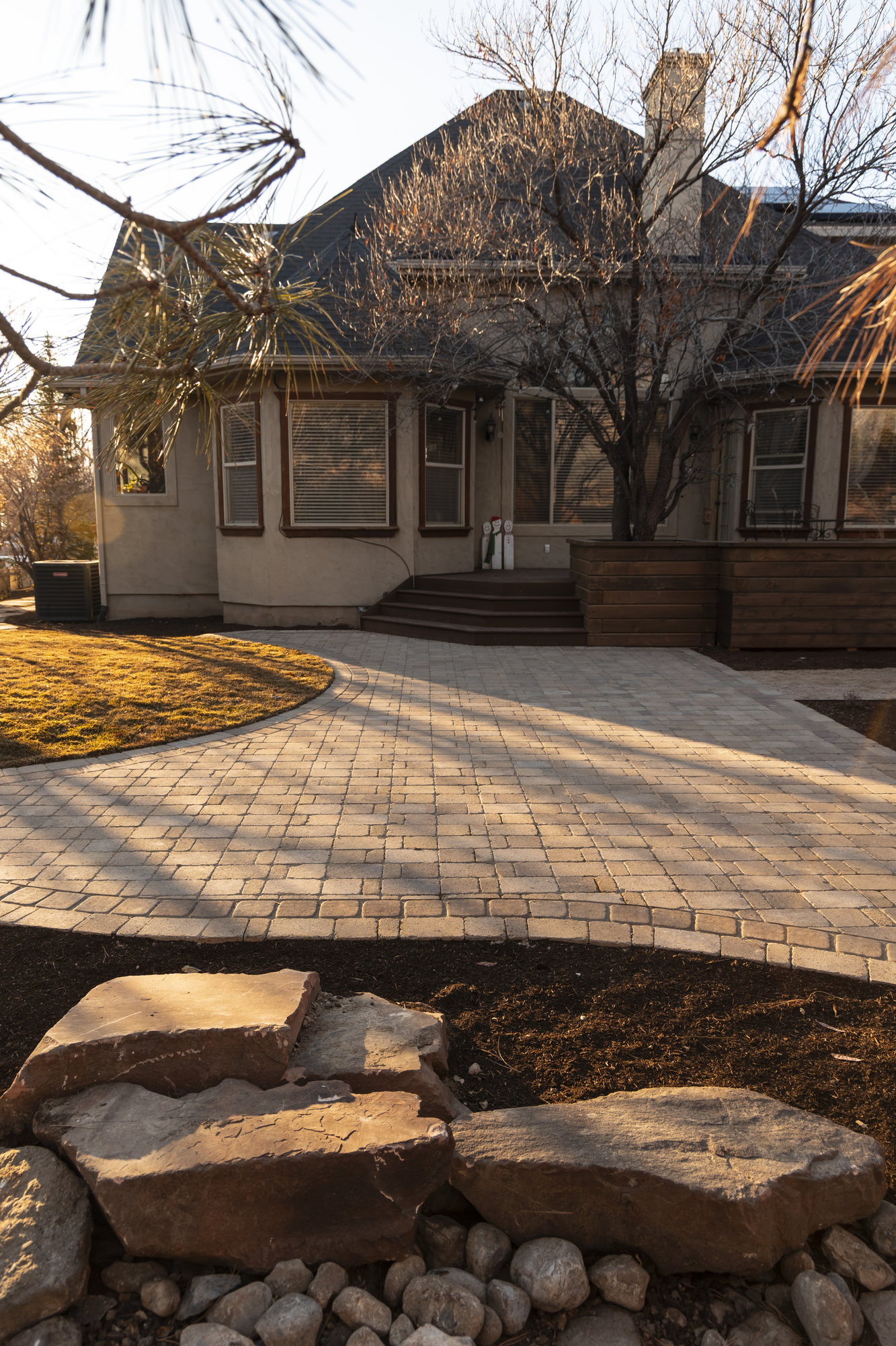 Circular paver drive court with boulder planting beds in low winter sun