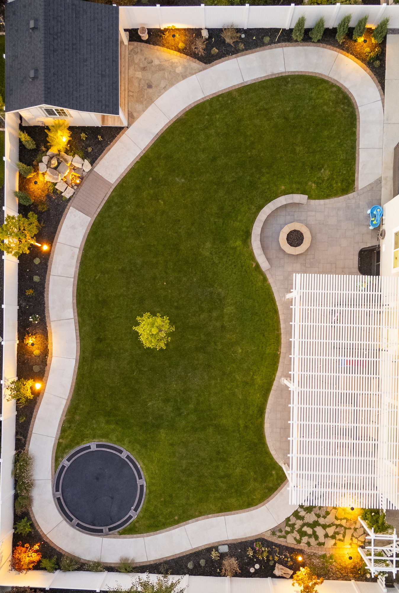 Overhead view of a curved lawn with path lighting at dusk